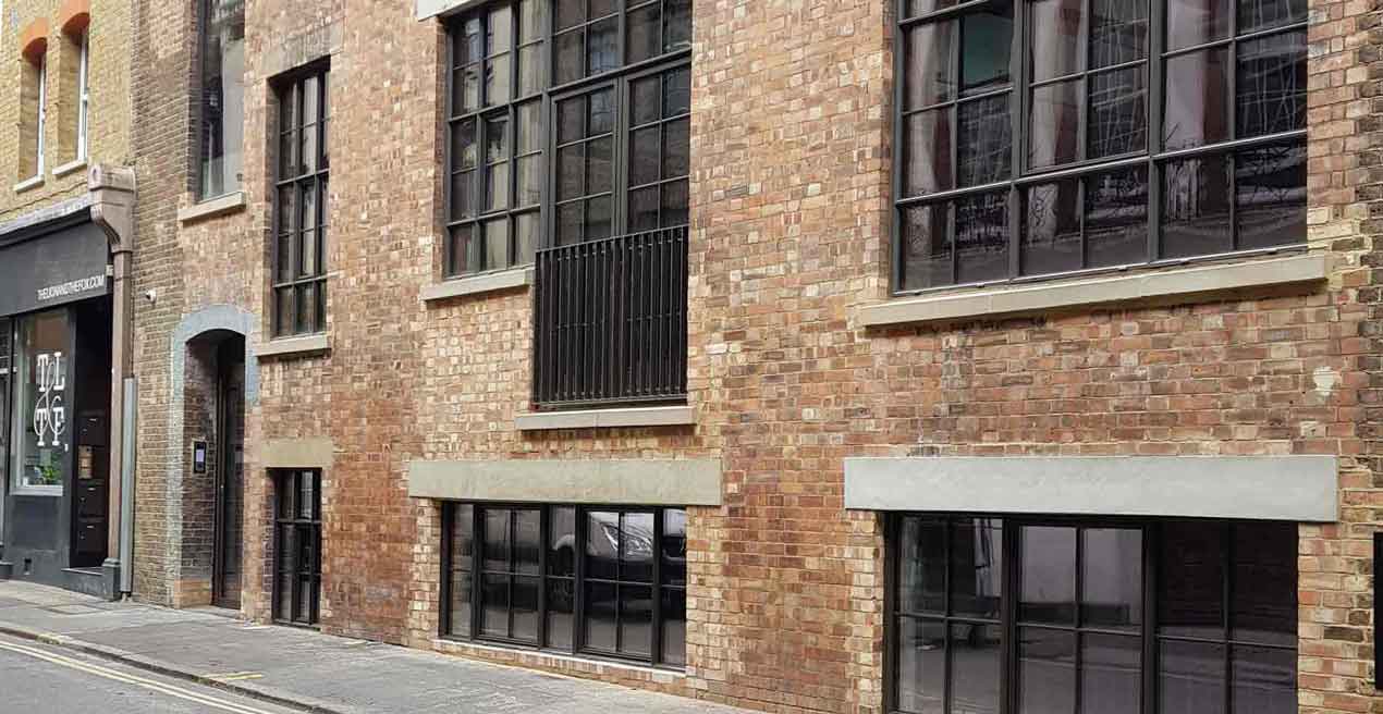 A brick wall with dark windows on a street in Hatton Garden, London