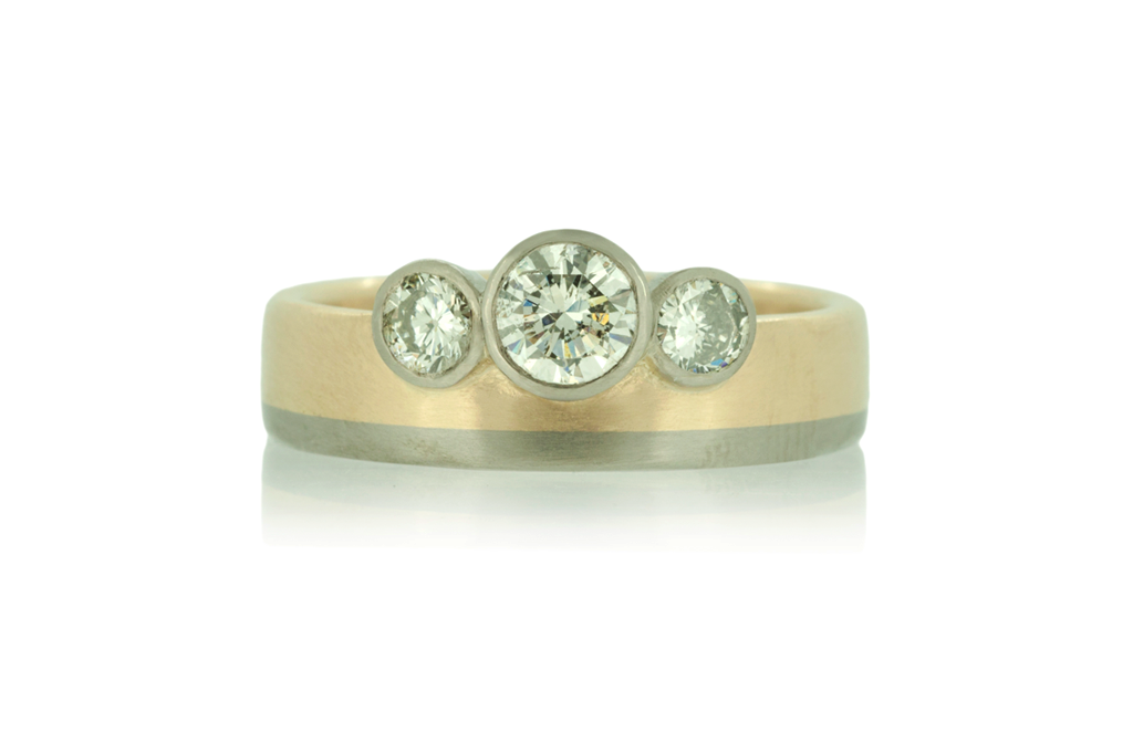 Two tone ring in yellow and white gold with three diamonds on white background.