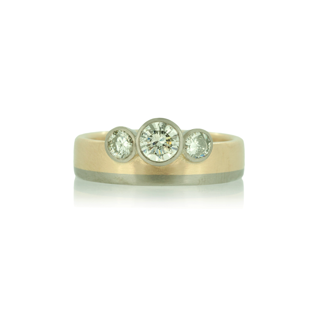 Two tone ring in yellow and white gold with three diamonds on white background.