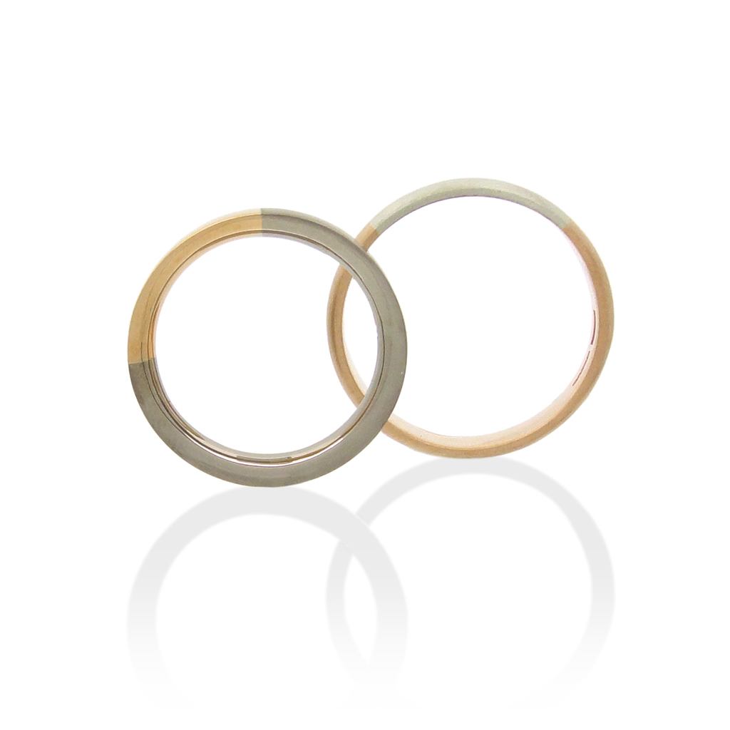 Two wedding rings in rose and white gold standing upright on a white background.