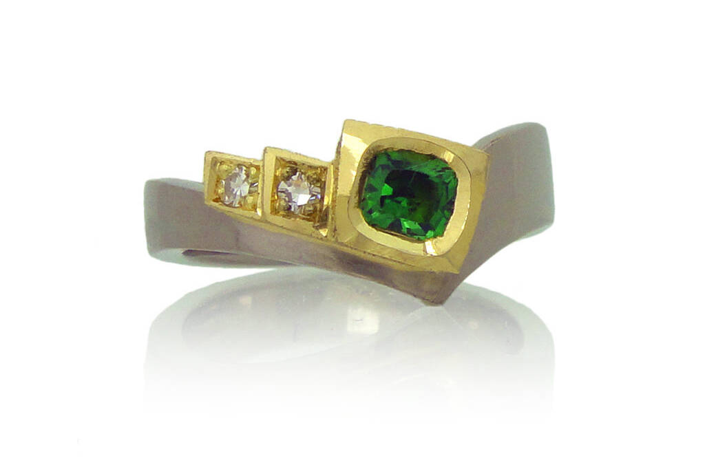 Front view of tsavorite and diamond ring on white background.