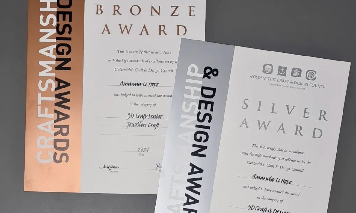 two Goldmsiths craftsmanship and design awards certificates on a grey background