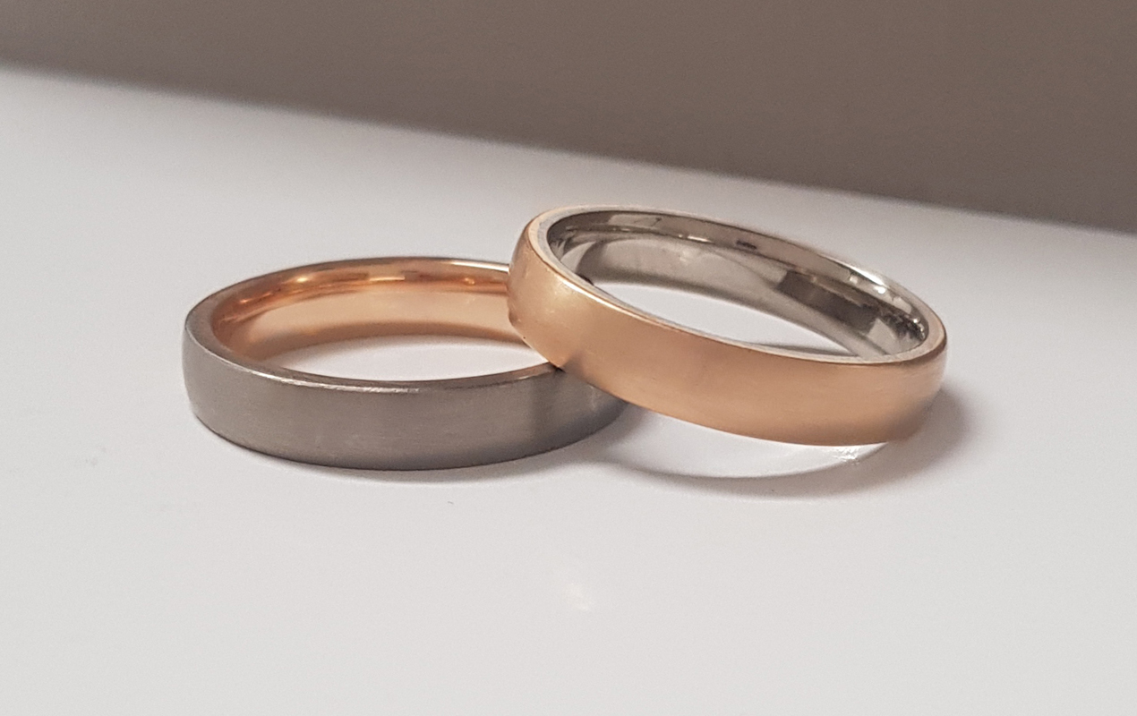 white and rose gold wedding rings, one stacked on top of the other against a grey background