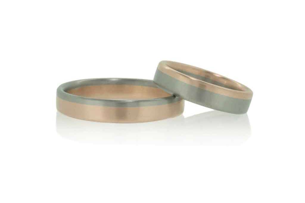 Two tone wedding rings in rose and white gold set against a white background.
