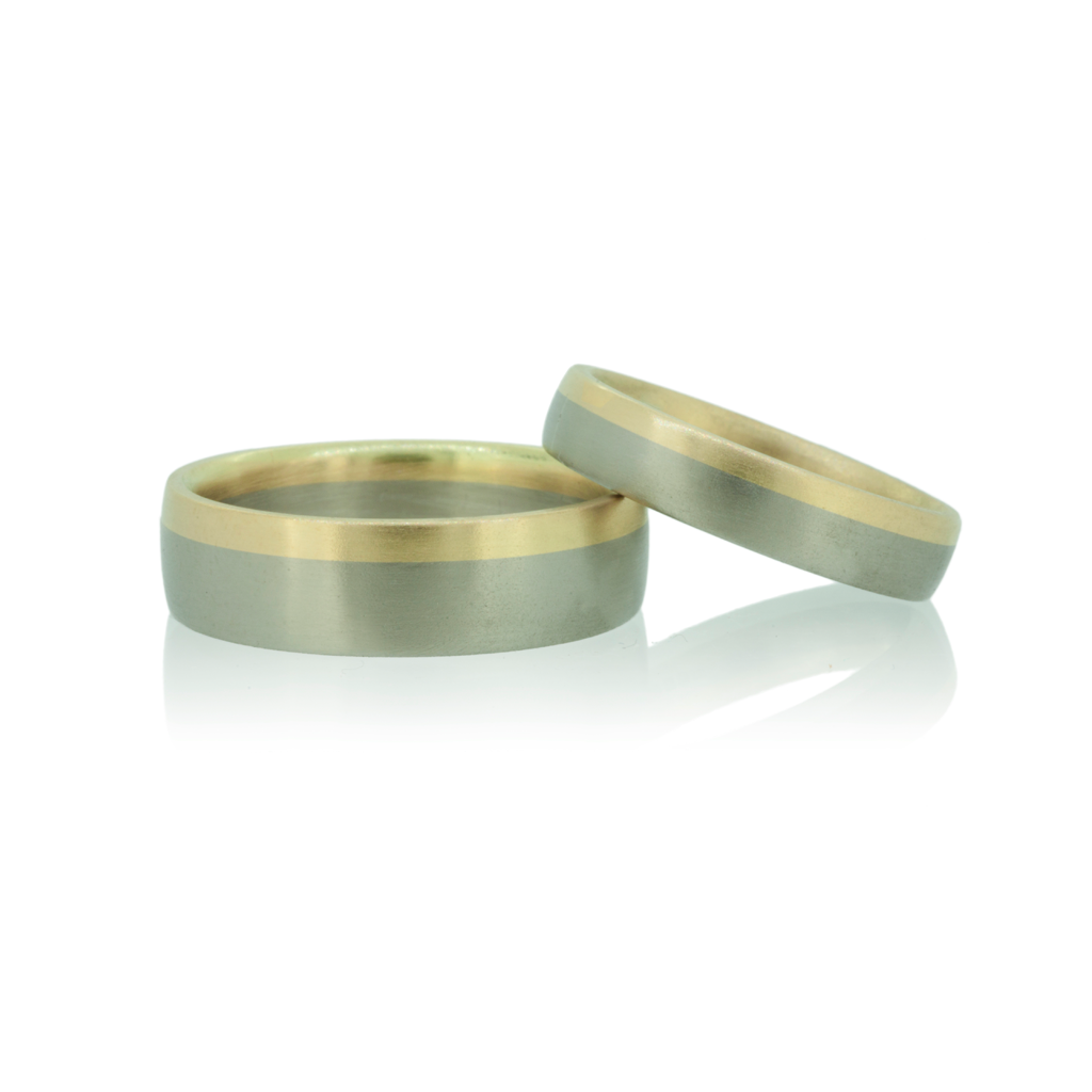 Two bi-metal wedding rings in yellow and white gold set against a white background.