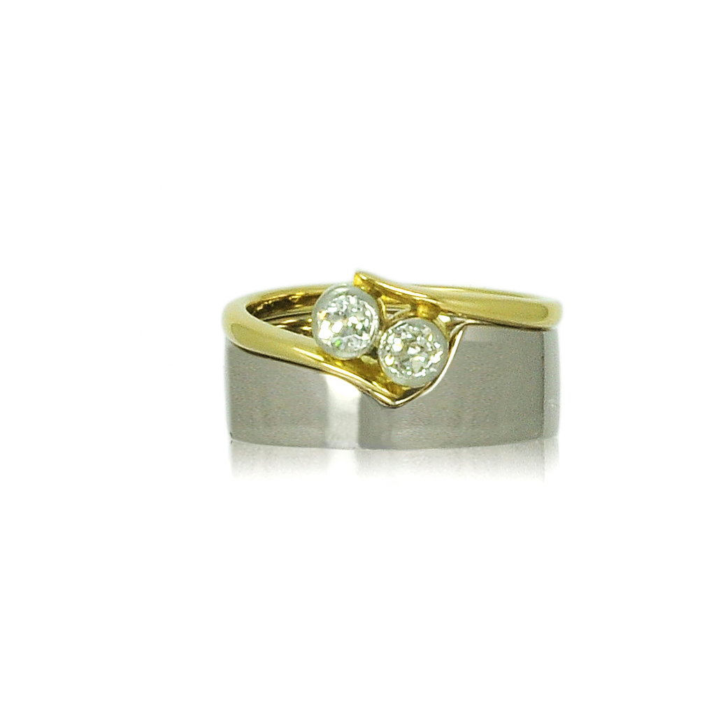 Top view of a white gold wedding band and vintage yellow gold engagement ring on a white background