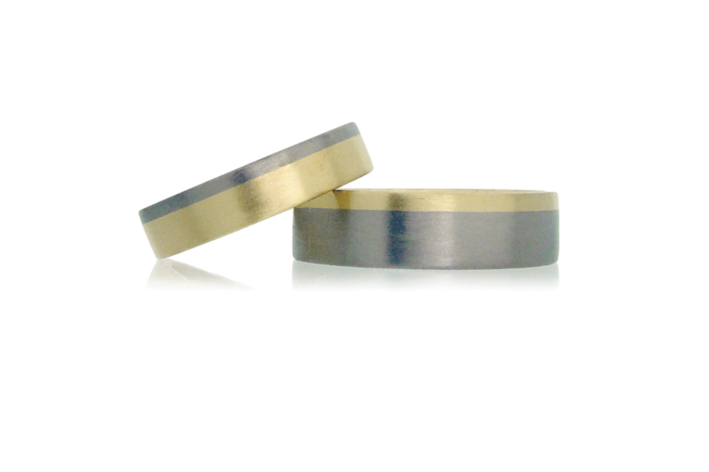 Two bi-metal wedding rings in yellow and white gold set against a white background.