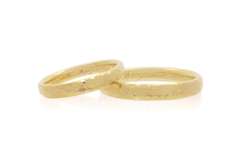 A pair of yellow gold wedding ring laying on a white background.
