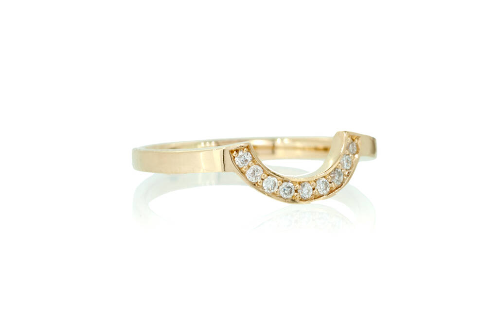Shaped wedding band with diamonds set against a white background.
