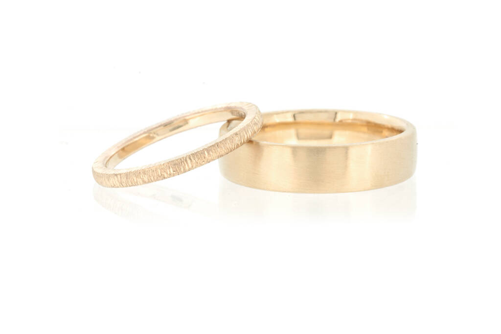 A pair of yellow gold wedding rings on a white background.