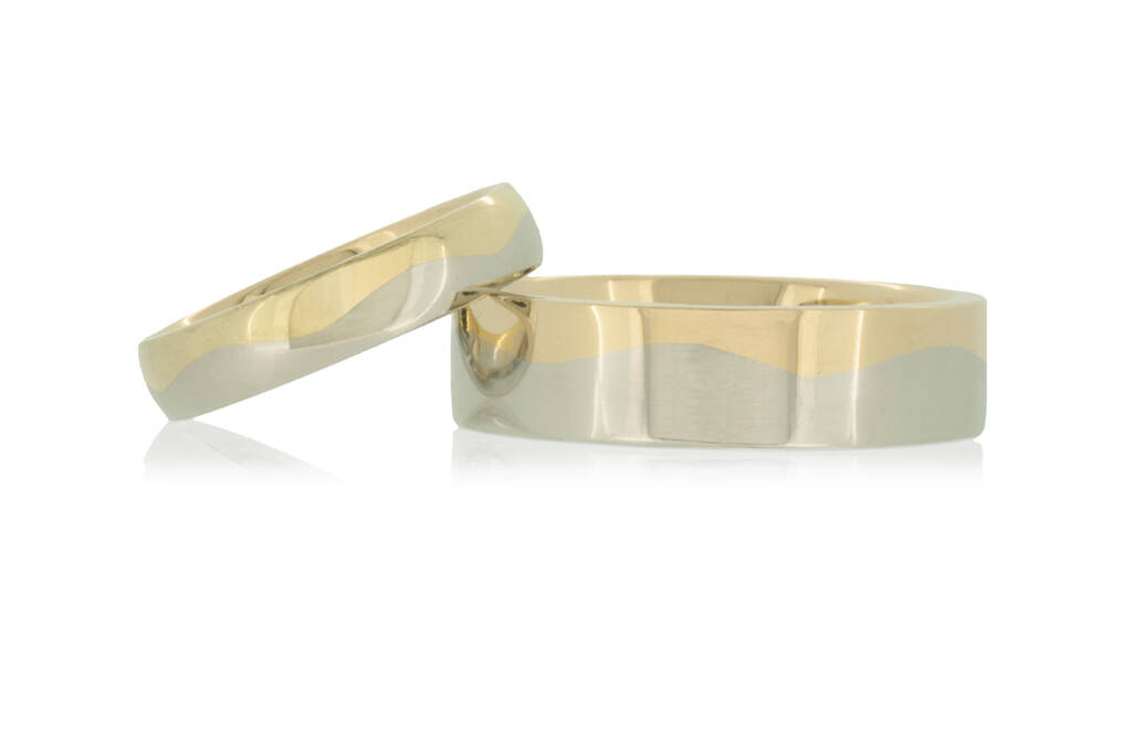 Yellow and platinum wedding rings with wave design set against a white background.