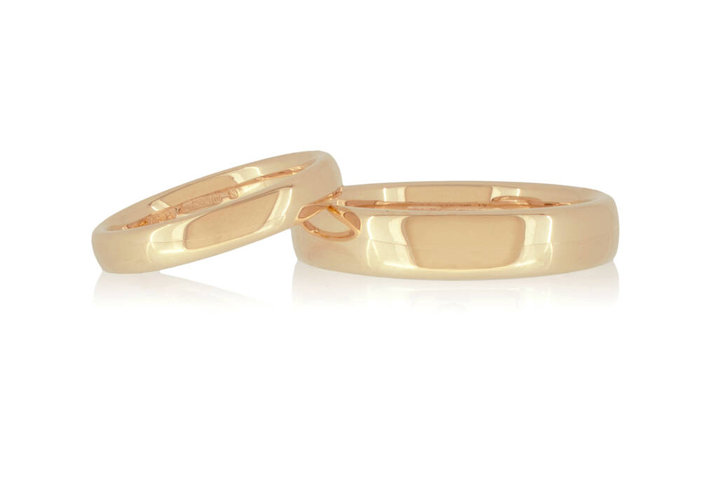 Two rose gold wedding rings on a white surface set against white background