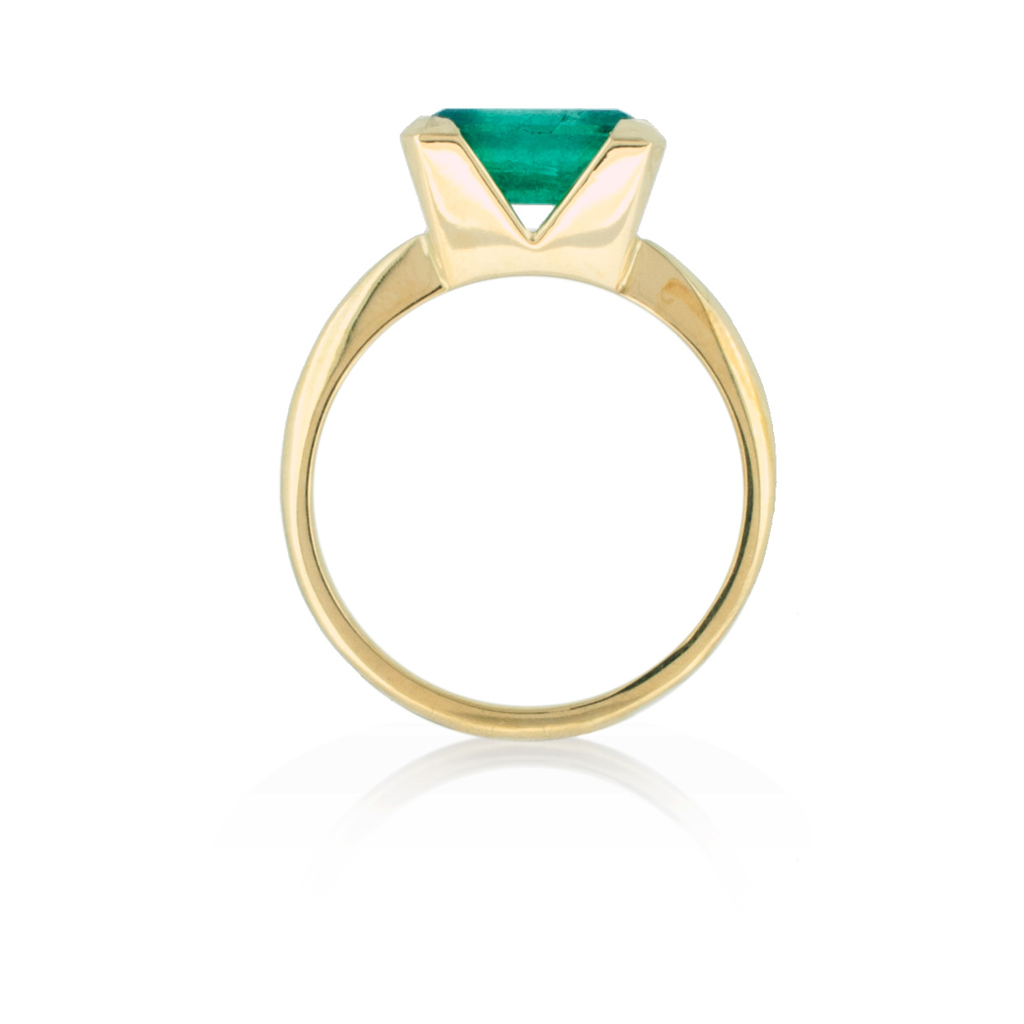 side profile of a bespoke emerald engagement ring, with a single square emerald held in a yellow gold setting and band, on a white background