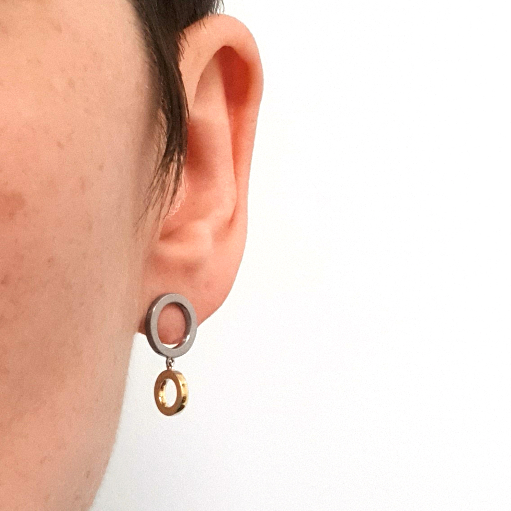 Two tone earrings in yellow and white gold circles on a person's ear and with a white background.