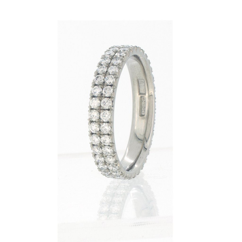 Wedding ring with a double row of diamonds standing upright on a white background.
