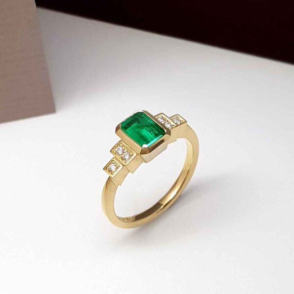 Art Deco emerald engagement ring with stepped diamond shoulders
