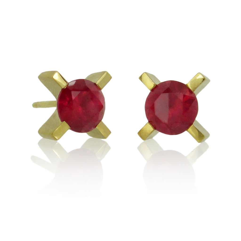 Ruby earrings in a yellow gold xx setting on a white background.