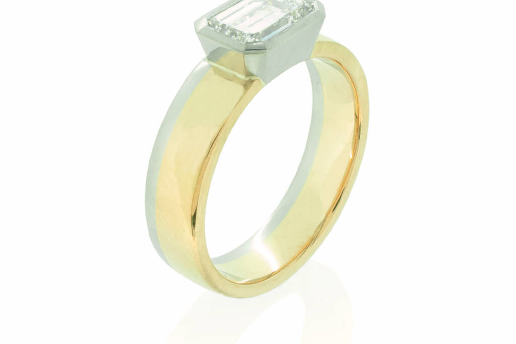 Two tone wedding band made with platinum and gold and horizontally set emerald cut diamond