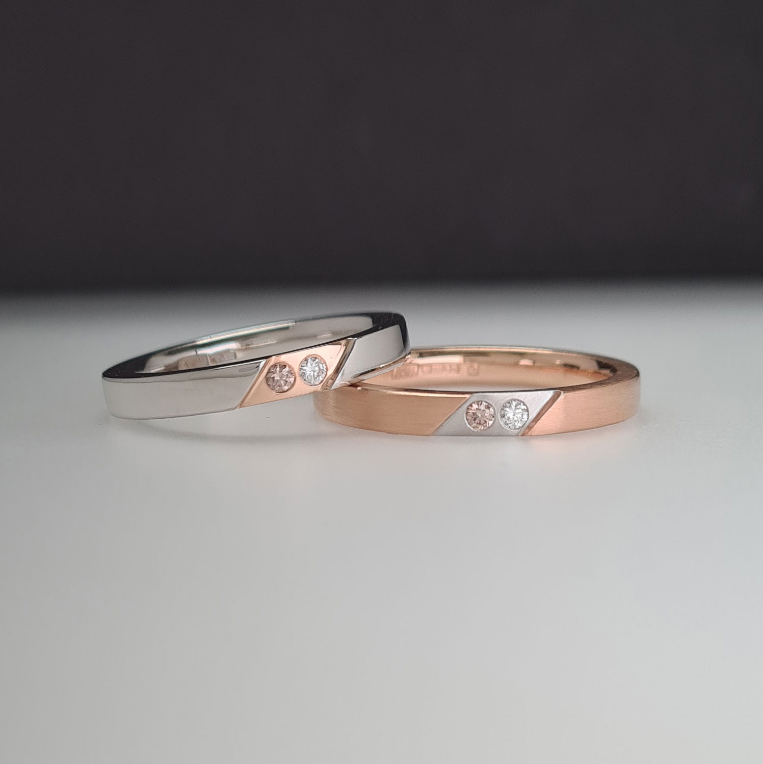 Two rings in rose gold and platinum with inset colourless and champagne diamonds on a black and white background.