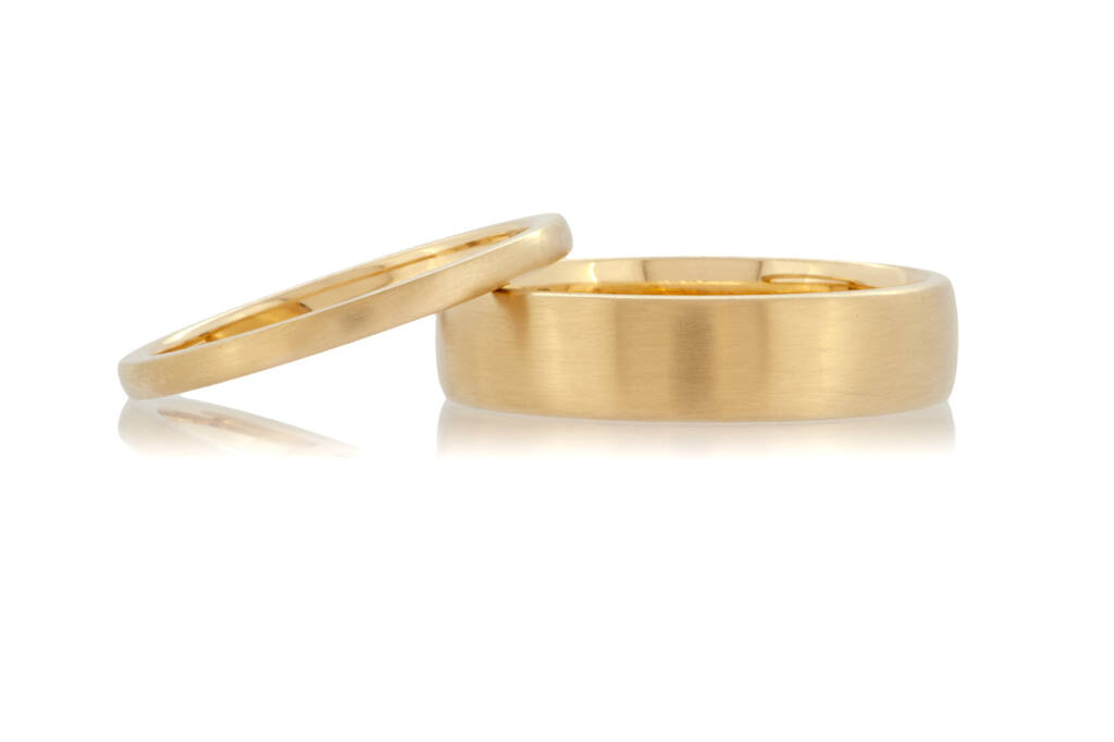 A pair of 18ct blush yellow gold wedding rings with a matte finish on a white background.