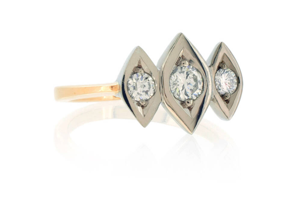 A trinity diamond ring with three diamonds in navette shaped white gold settings on a light rose gold band on a white background.