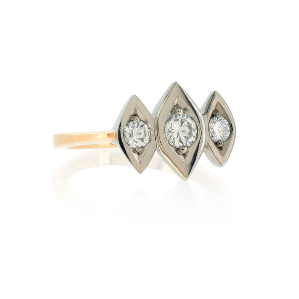 A trinity diamond ring with three diamonds in navette shaped white gold settings on a light rose gold band on a white background.