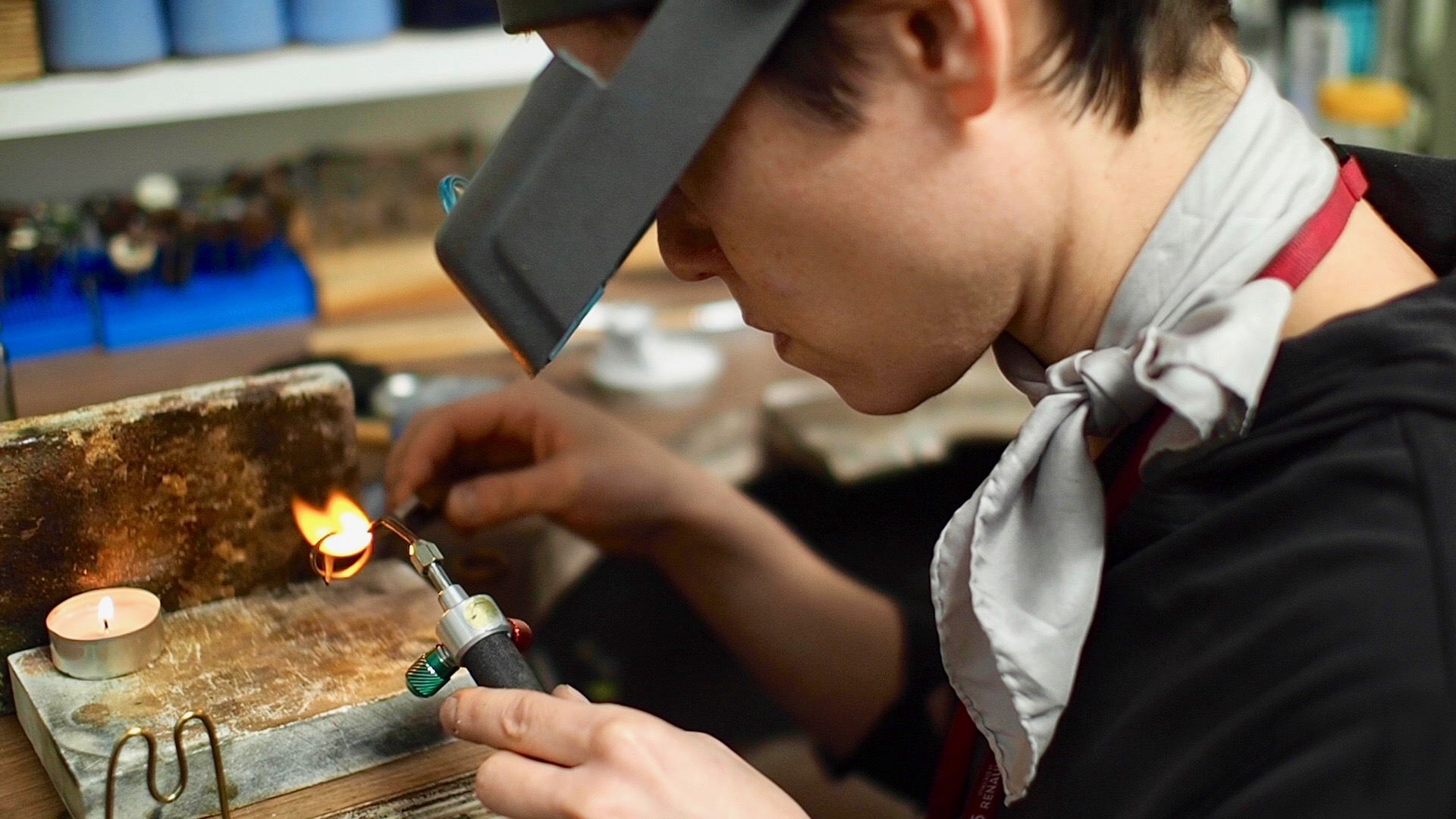 jewellery maker wearing goggles applying a flame to a ring in a jewellery workshop setting