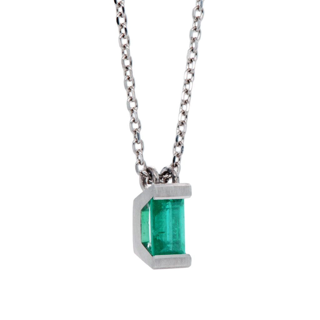 Emerald pendent with rectangular stone with platinum setting and chain on a white background