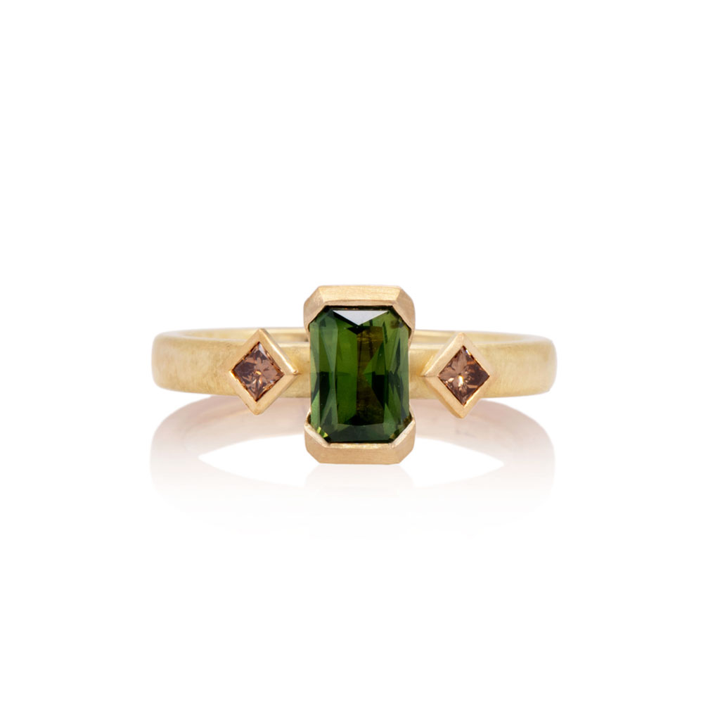 Art deco inspired engagement ring with a central green sapphire and champagne diamonds on a gold band against a white background