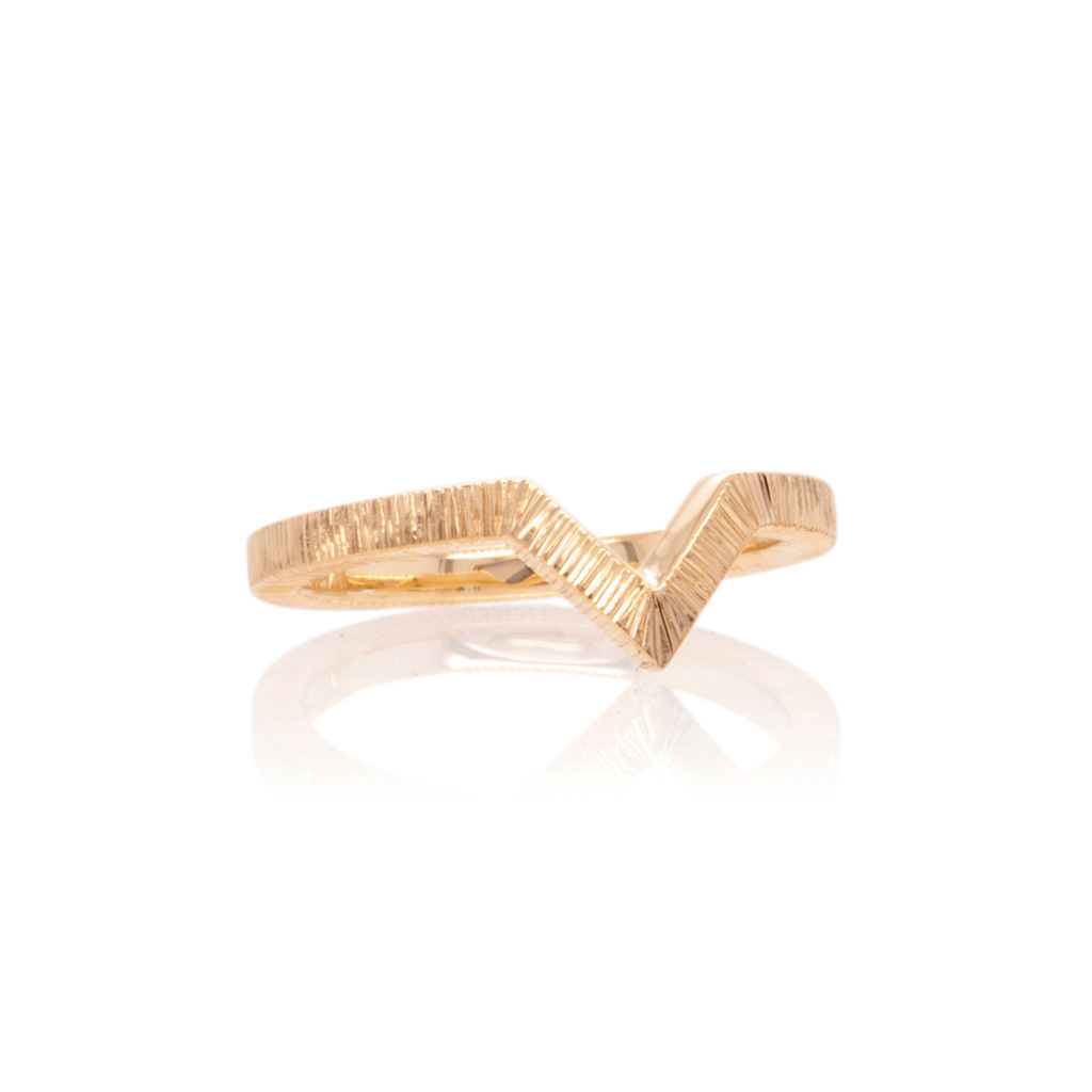 Yellow gold wedding ring with a chevron shaped detail and an engraved textured finish on a white background.