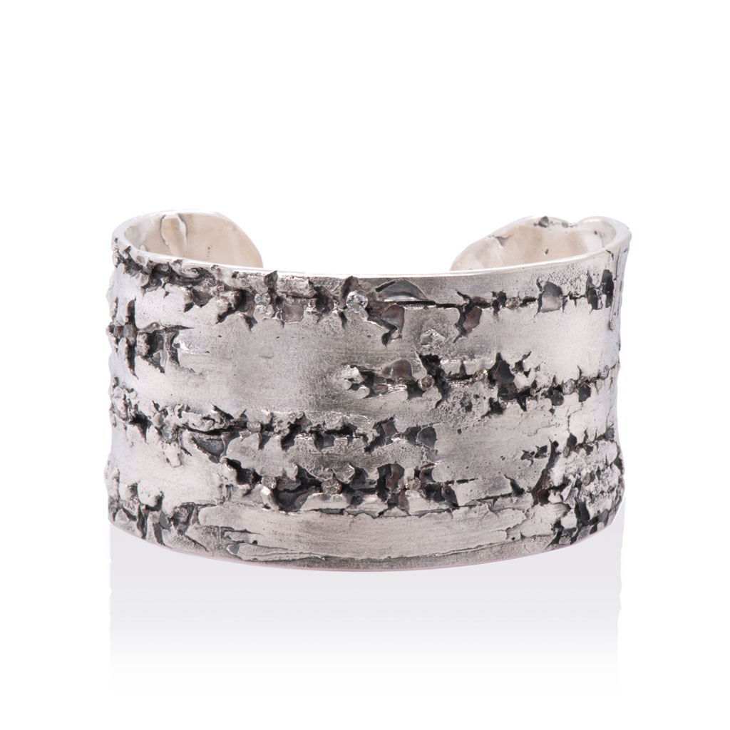 silver cuff bracelet with rough texture of silver birch bark against a white background