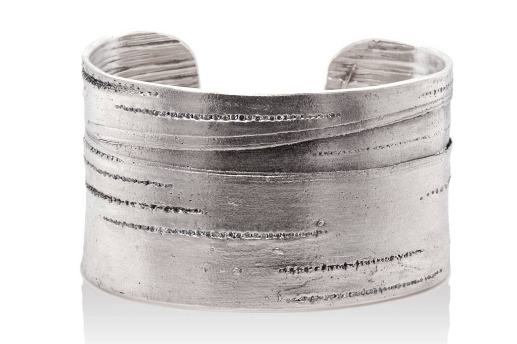 silver cuff bracelet with lined texture of silver birch against a white background