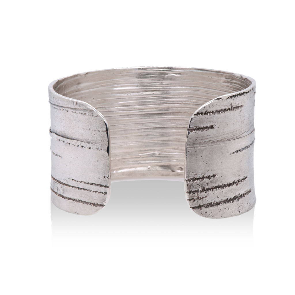 the back of a silver cuff bracelet featuring the texture of silver birch bark against a white background