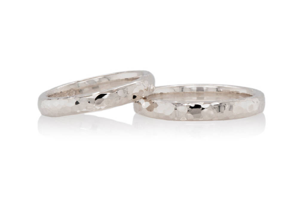 pair of white gold hammered wedding rings on a white background