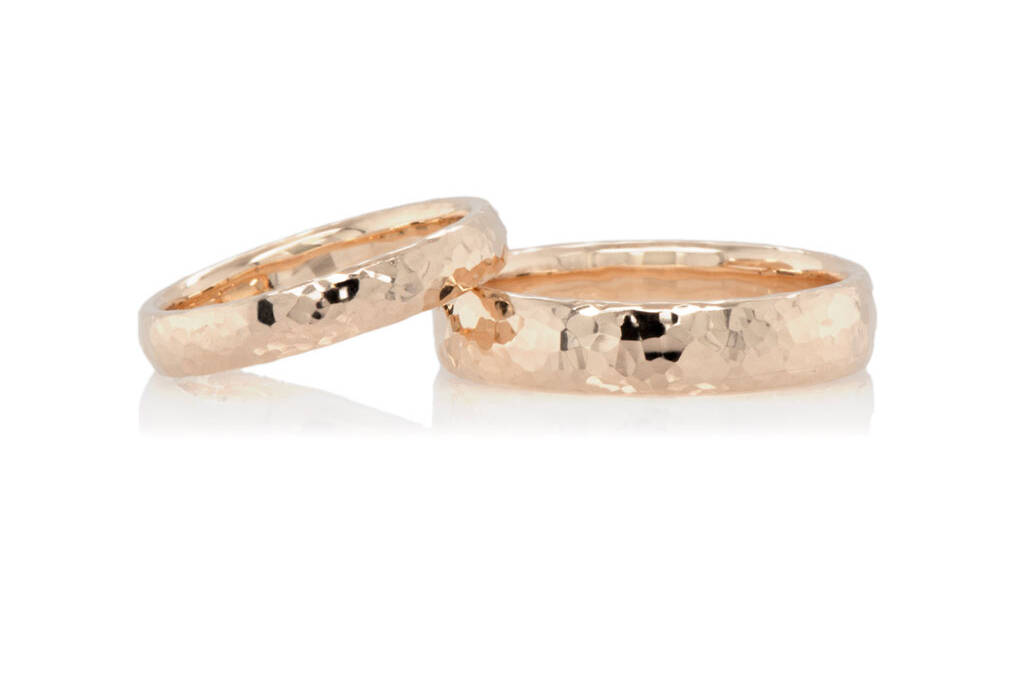 a pair of gold wedding bands with hammered texture on a white background