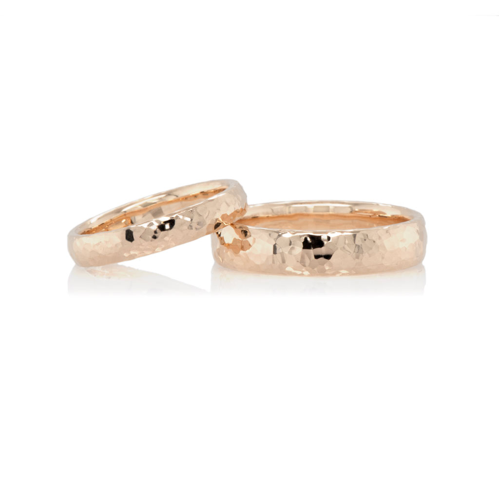 a pair of gold wedding bands with hammered texture on a white background