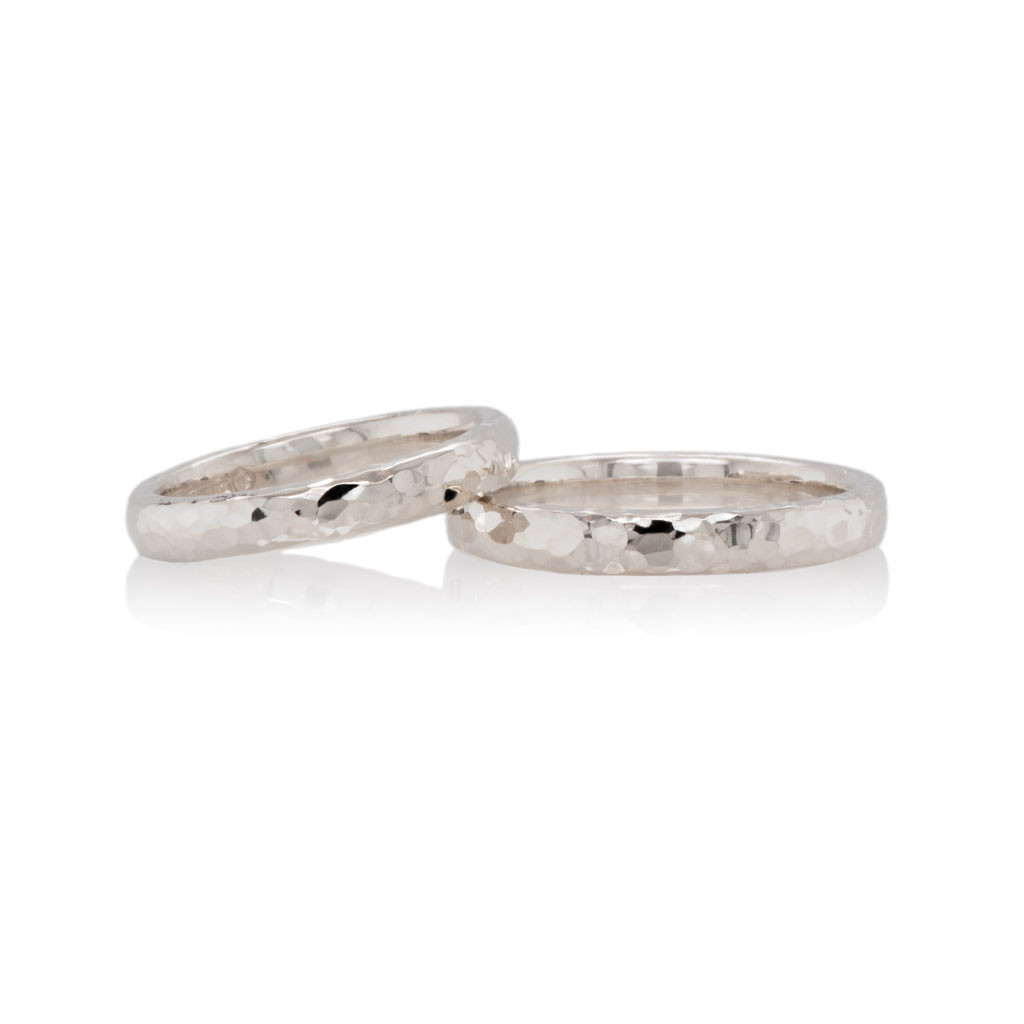 pair of white gold hammered wedding rings on a white background