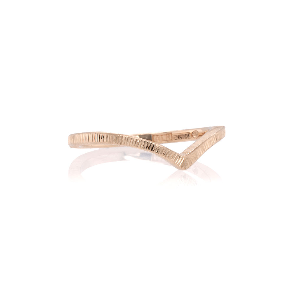 Gold wishbone wedding ring with short engraved lines cut around the band. Ring shown with a white background.