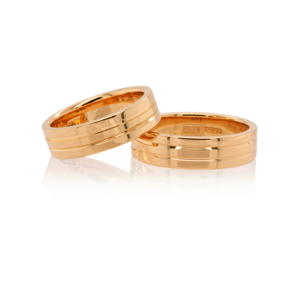 Two 22k rose gold wedding rings, one laying on the other, on a white background.