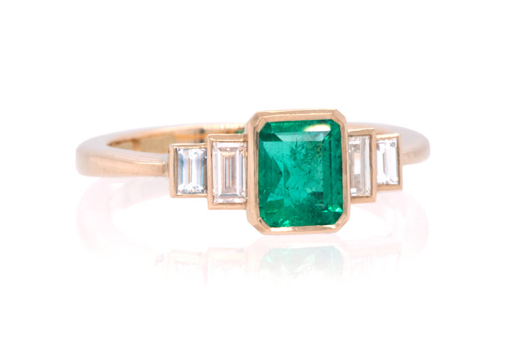 Front view of Emerald and baguette diamond engagement ring on white background.