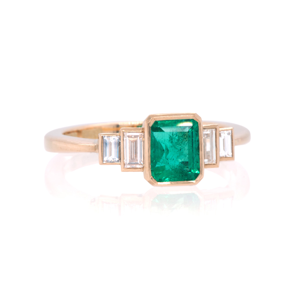 Front view of Emerald and baguette diamond engagement ring on white background.