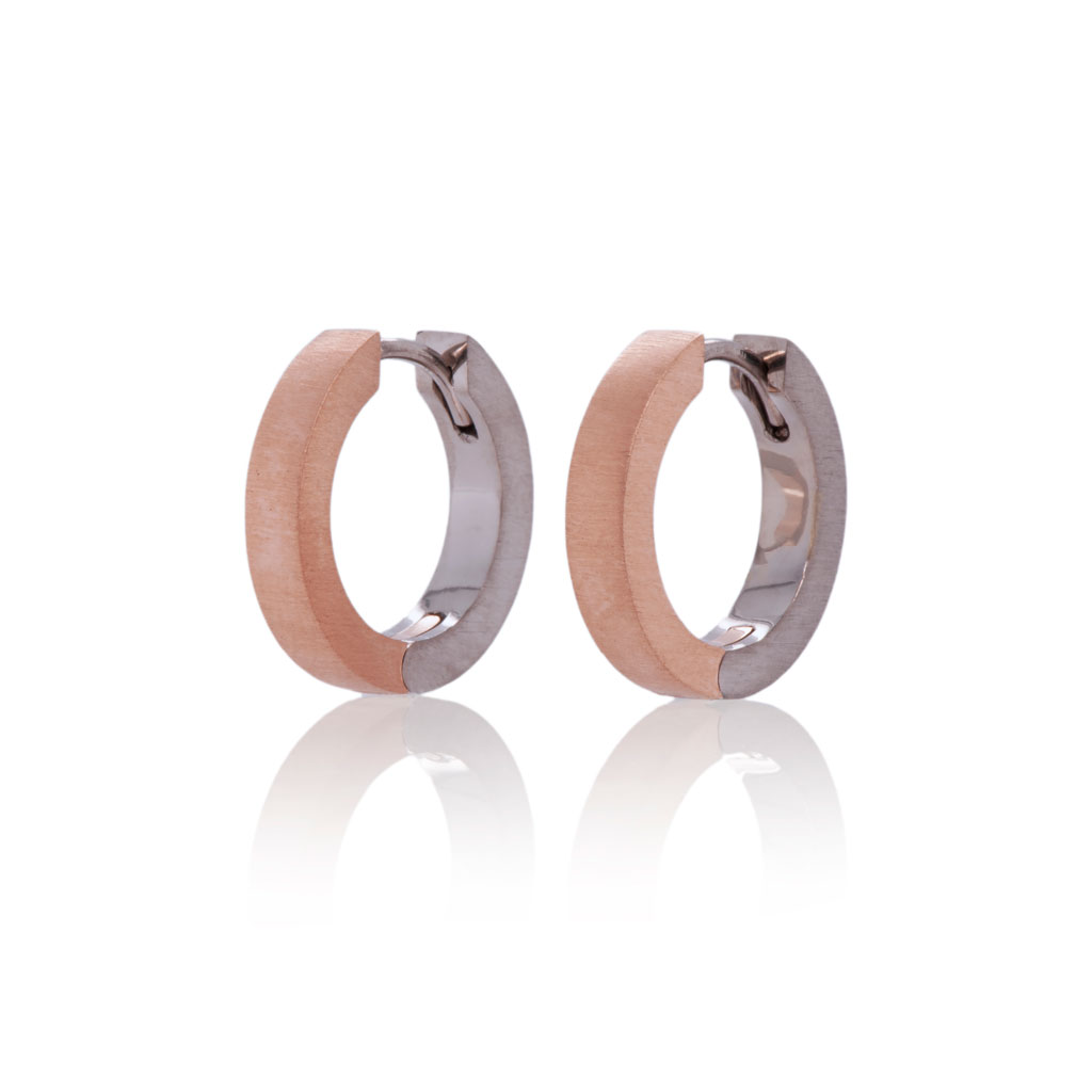 A pair of two tone hinged hoop earrings standing upright against a white background.