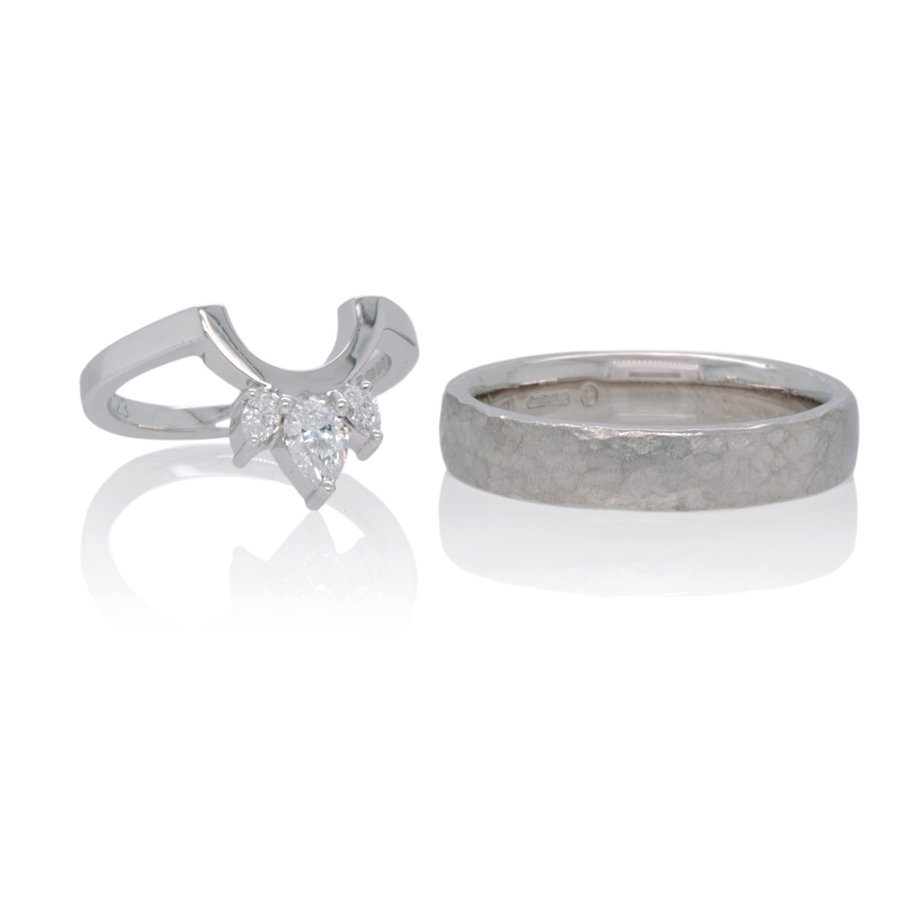 WedFit fitted wedding ring in white gold with 3-pear cut diamonds next to a platinum wedding band on a white background.