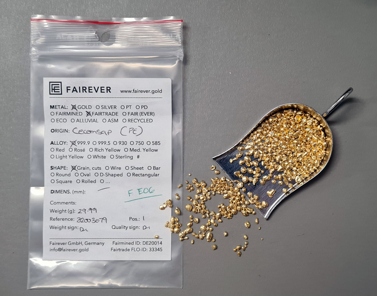 Pure gold grain overflowing from a silver-coloured metal scoop onto a plastic baggie labelled 