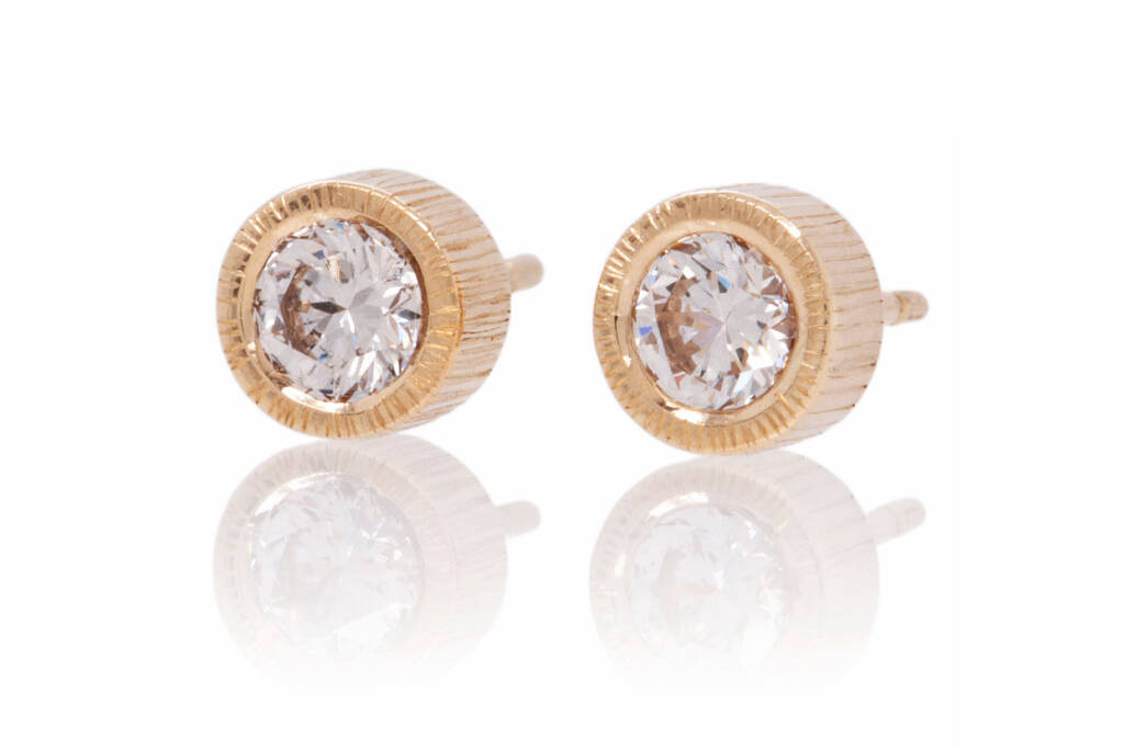 Textured earring studs in yellow gold set with round diamonds on a white background.