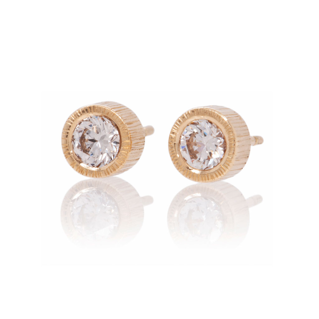 Textured earring studs in yellow gold set with round diamonds on a white background.